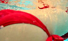 Katy Sorokas nada desnuda junto a la piscina en fondos rojos de bikini