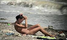 Mørkhåret naken jente går rundt naken på en strand