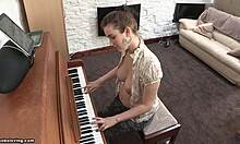 Leikkisän näköinen brunette, jolla on pirteät tissit, soittaa pianoa yläosattomissa
