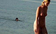 Μεγαλόστηθη ξανθιά κάνει πράγματα σε μια παραλία γυμνιστών, δείχνοντας καυτή
